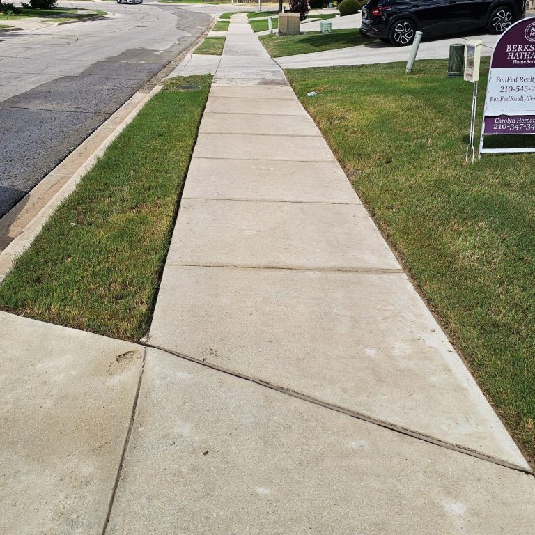 Cleaned long driveway Before and after view of a driveway, showcasing a clean, smooth surface and surrounding greenery.